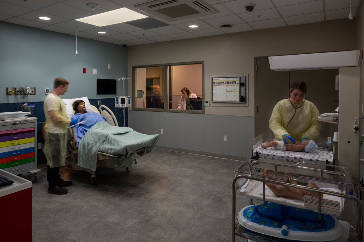 Simulation maternity ward room at UNH Health Sciences Sim Center with students, patient, and observation instructor.