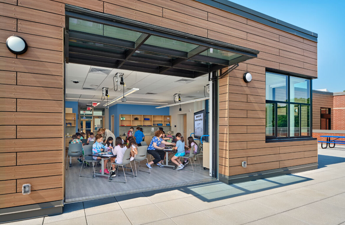 Classroom of students with a garage door leading out to a patio.